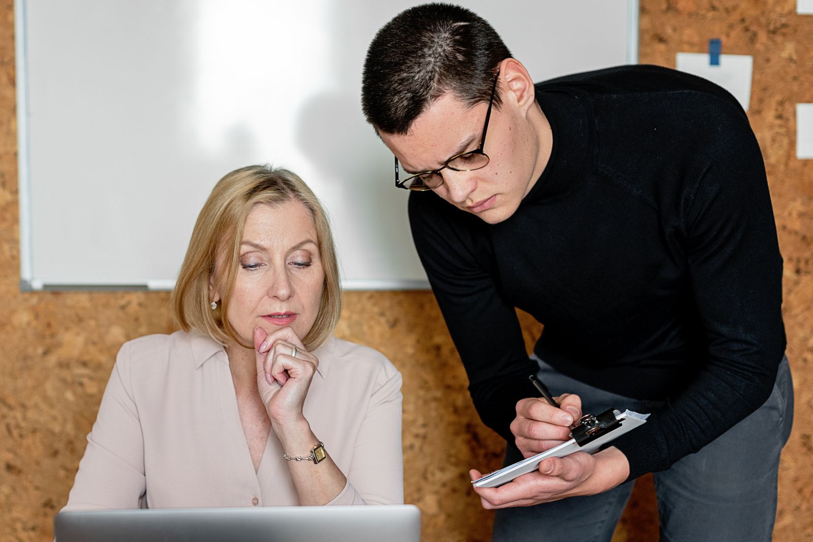 A manager and an employee reviewing a record together and taking notes