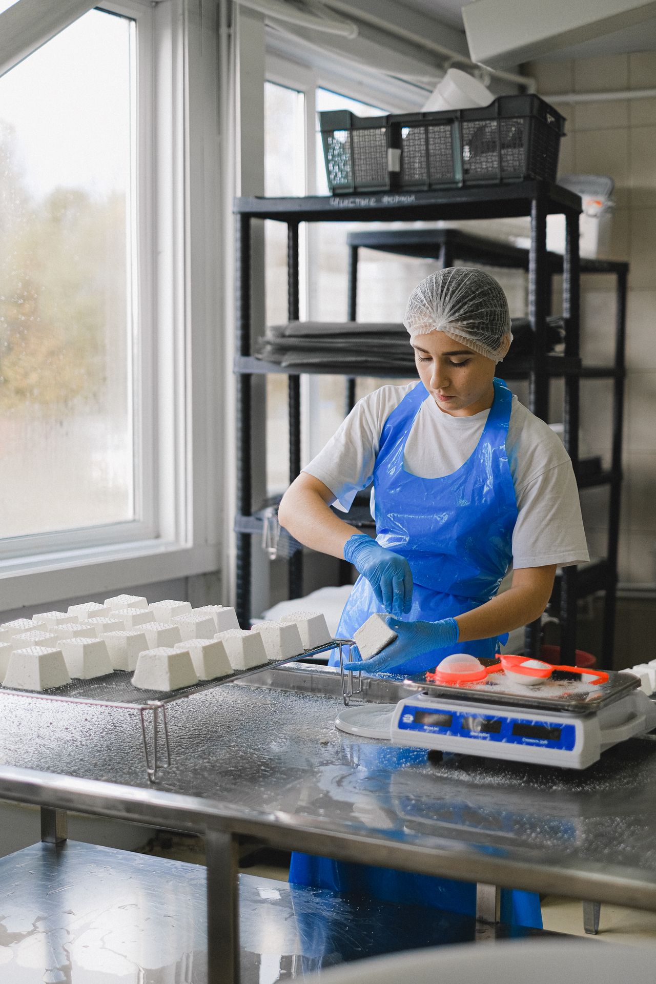 A food-production worker in hygiene protective equipment processing product
