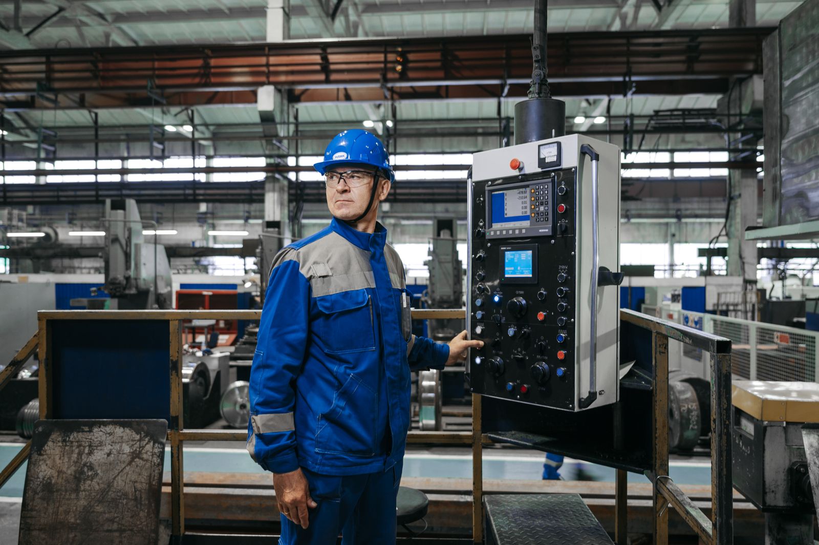 A production operator at a machine control station on the factory floor